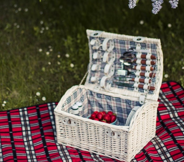 White picnic basket on a red blanket.