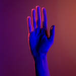 A raised hand in front of an orange and purple background