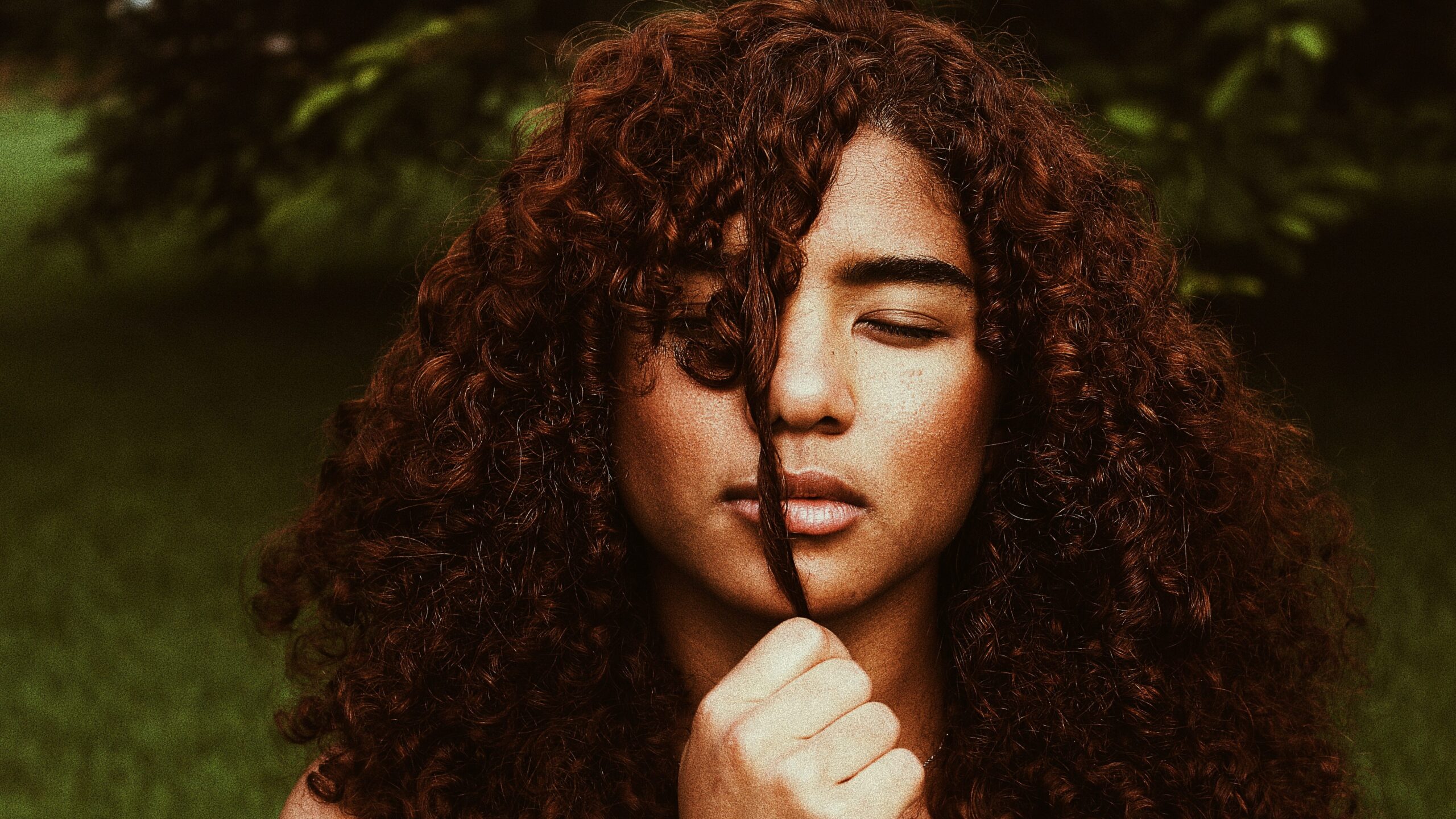 Woman pulling a strand of her curly hair in front of her face
