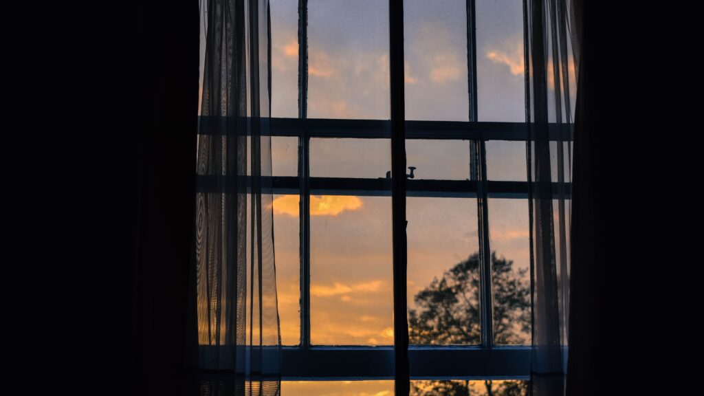 View of a sunrise through a curtained window