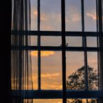 View of a sunrise through a curtained window