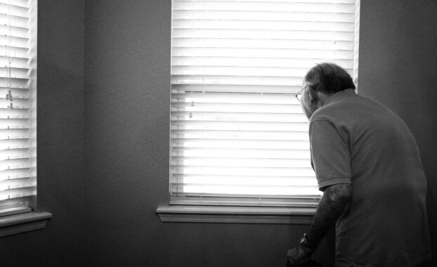 Elderly man looking out a window