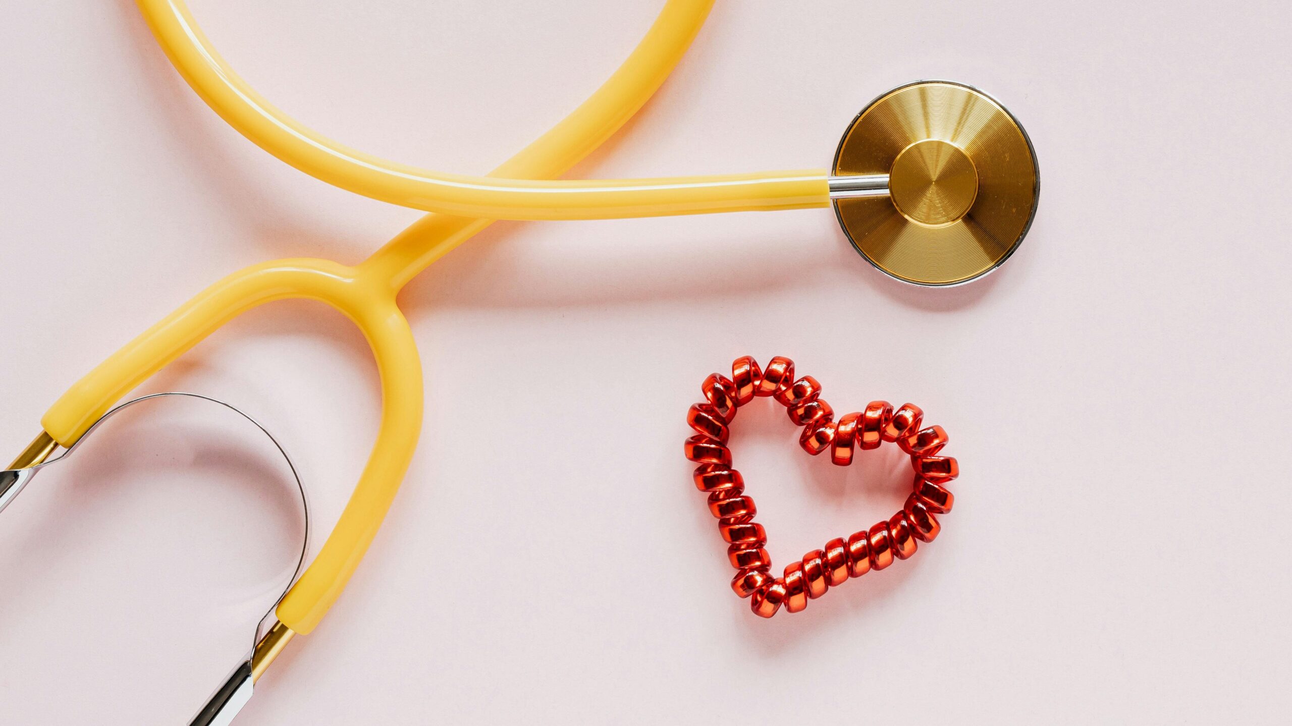 Yellow stethoscope with a red heart-shaped coil next to it 