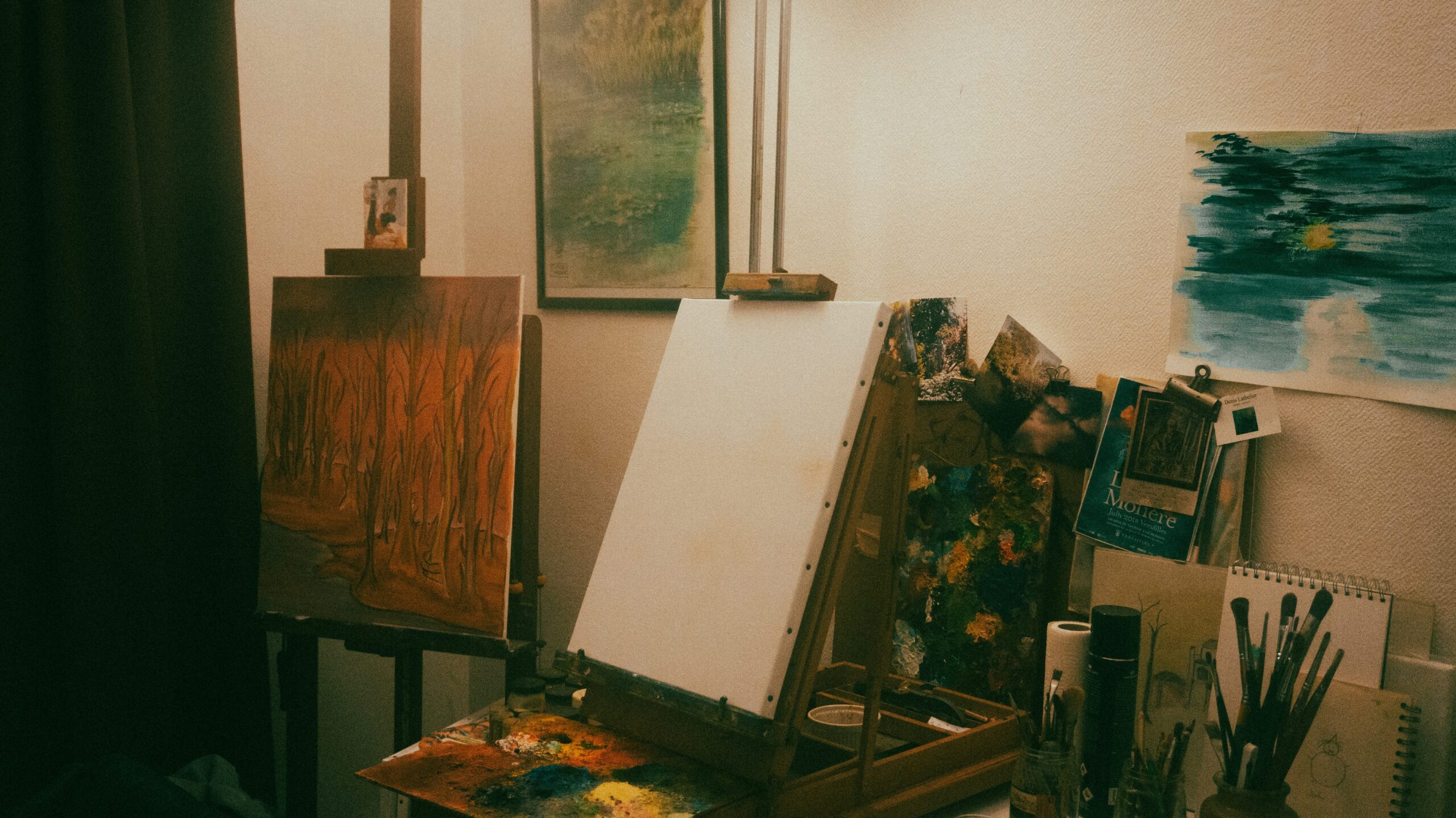 A room filled with paintings, canvas and paintbrushes