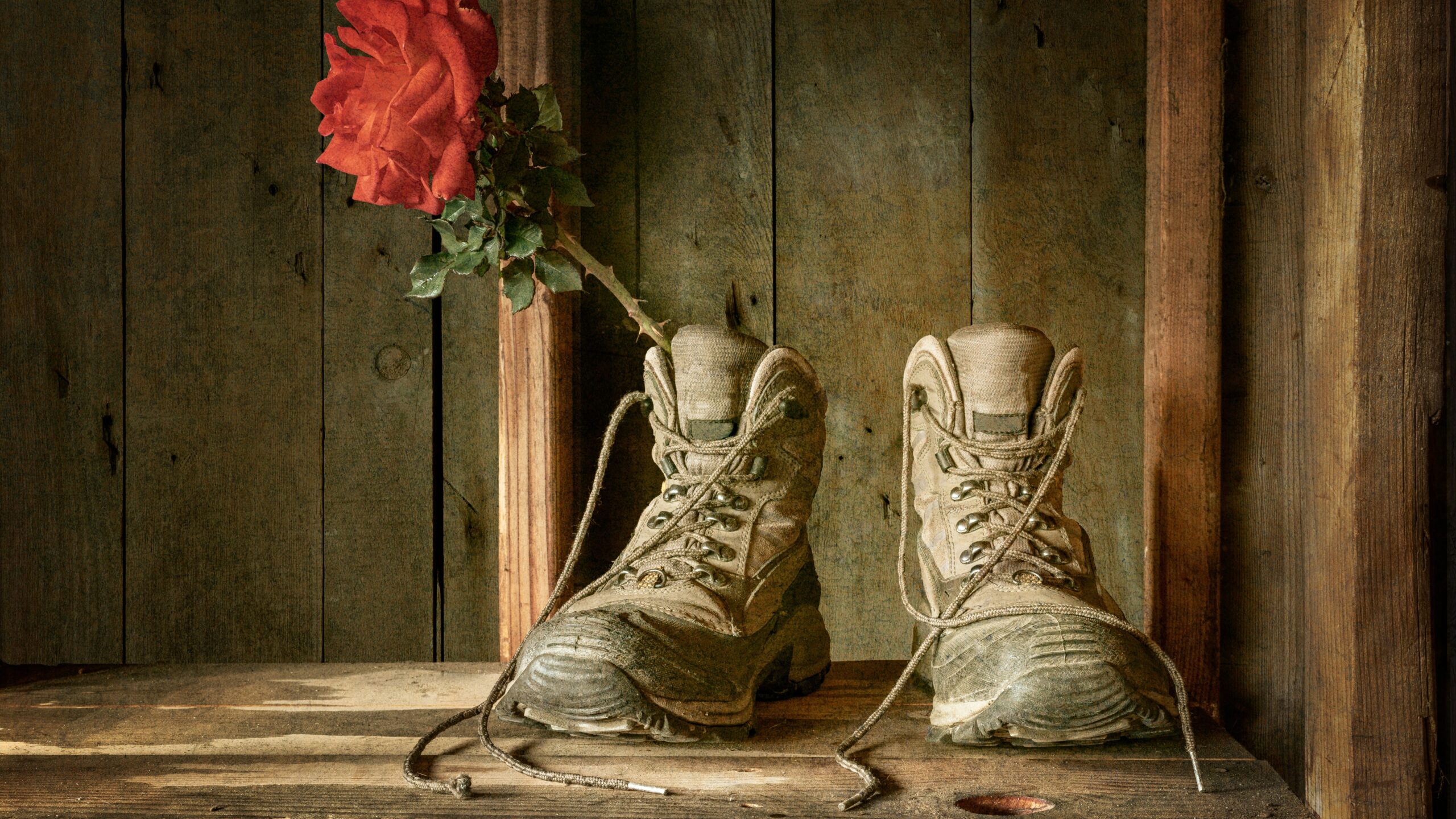 A pair of work boots with a rose inside one of them