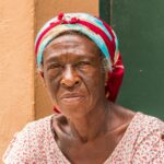 Elderly black woman with a colorful headscarf and a black and white dress