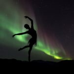 Ballerina dancing in front of Northern Lights