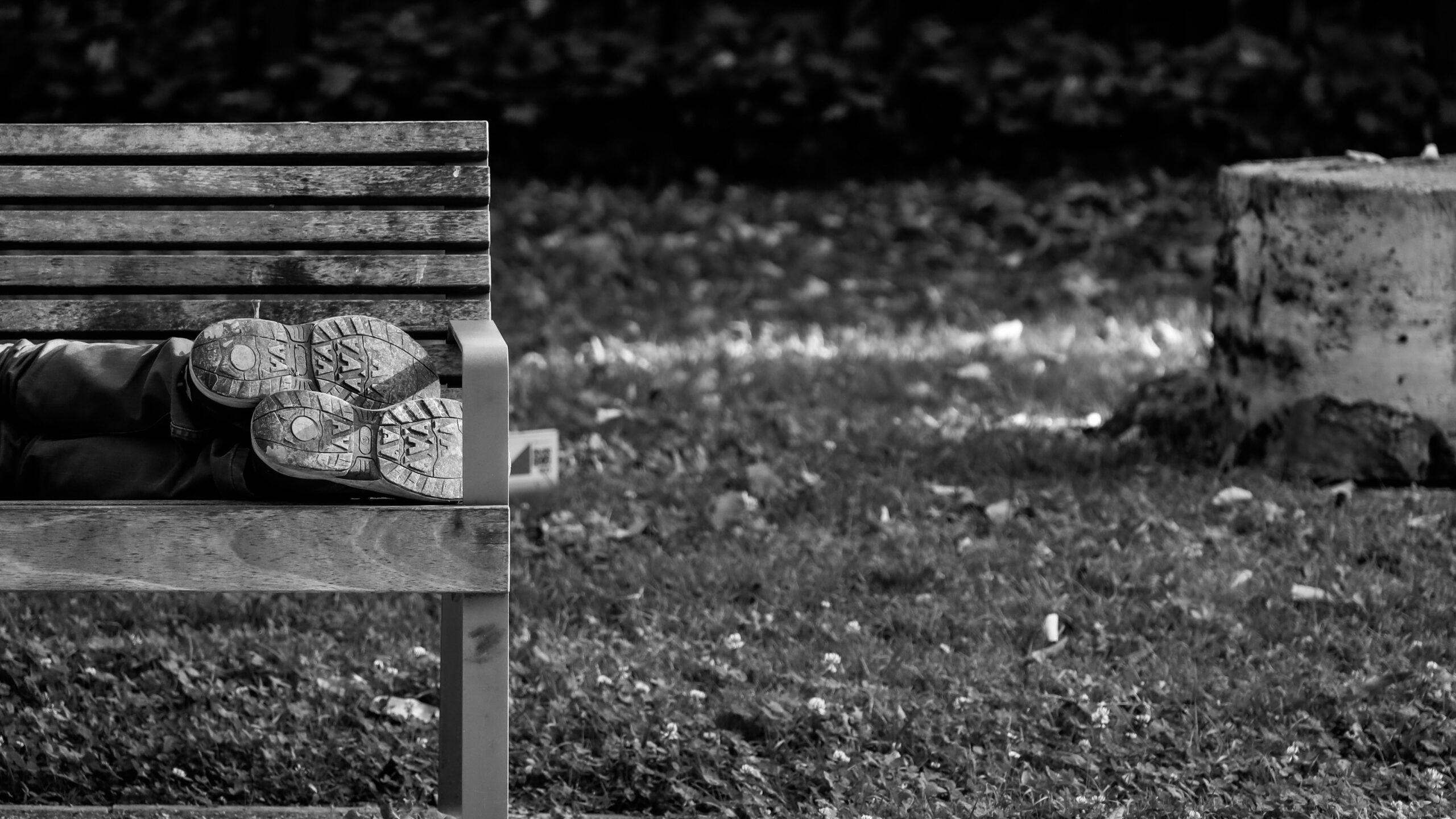 The feet of a body lying on a park bench.