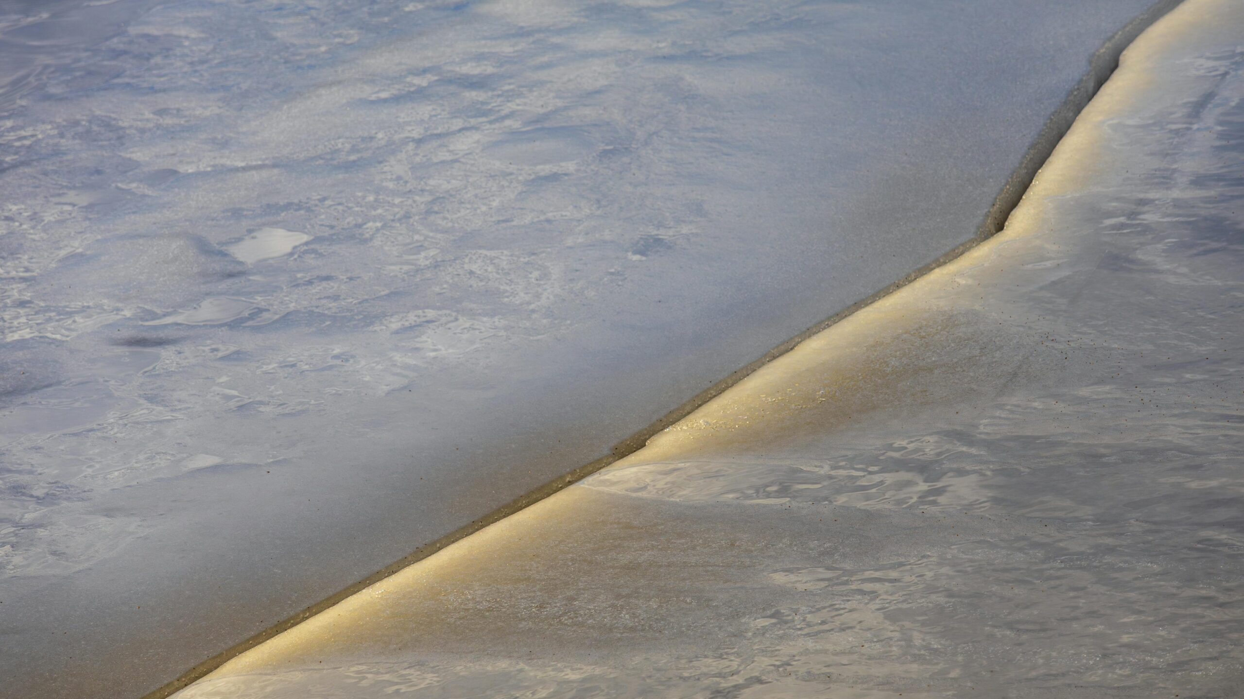 A long crack running through a sheet of ice.