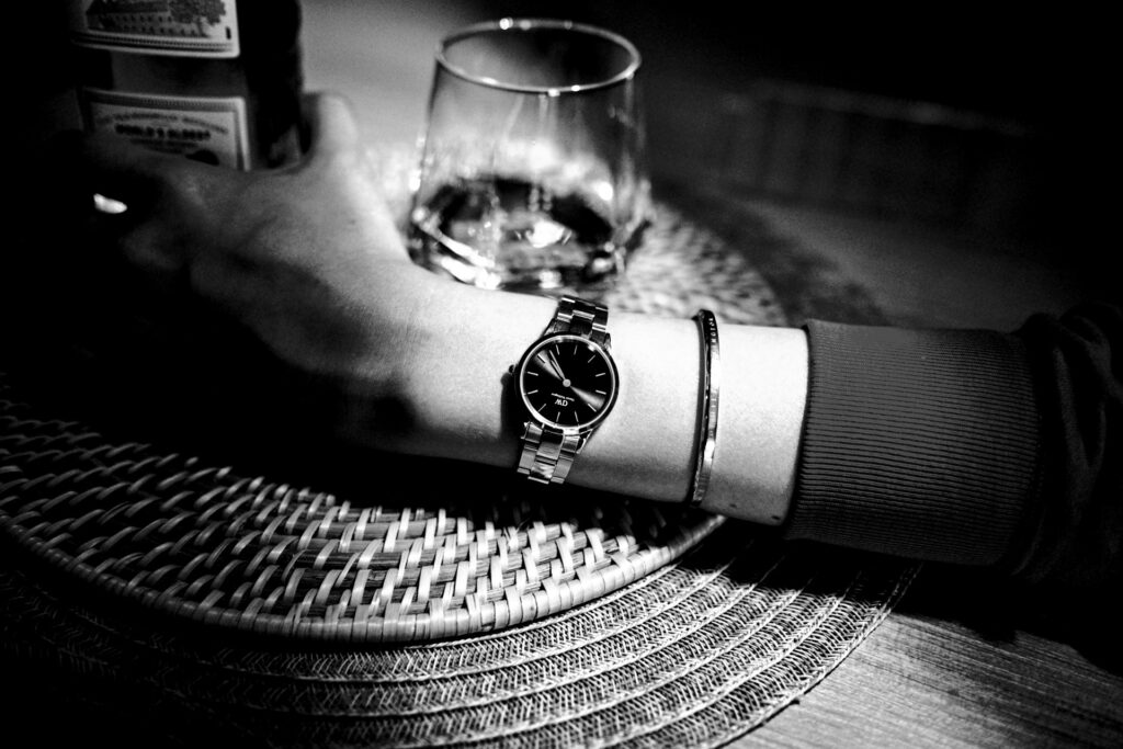 Image of an arm with a wristwatch cradling an alcoholic drink