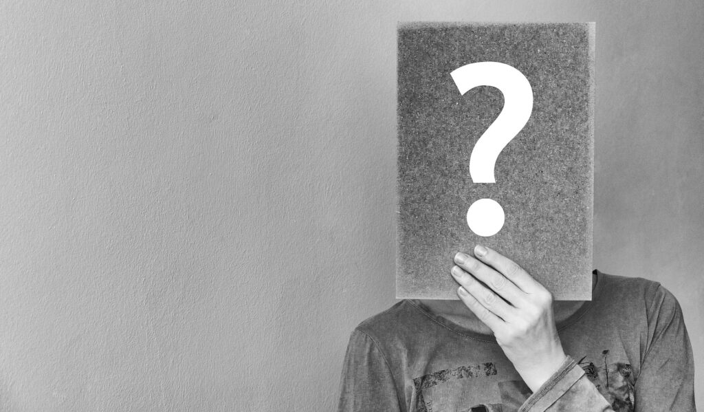A person holding a card with a question mark in front of their face