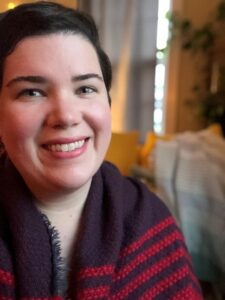 Kayleigh Michael, a smiling white woman with dark hair wearing a red and black top