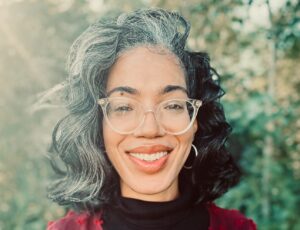 Nikki White, a Black woman with sweeping gray and black hair, clear-framed glasses, and a smile.