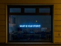 A neon sign that says, "What is Your Story?"