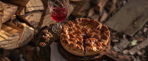 Photo by KATRIN BOLOVTSOVA: https://www.pexels.com/photo/a-baked-pie-and-a-glass-of-drink-on-a-tree-stump-5662359/