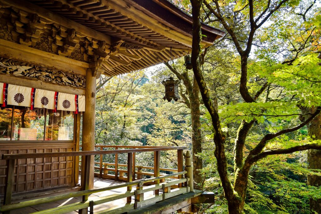 A Japanese bathhouse exterior set amid green woods. 