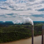 A polluted river with smokestacks in the foreground. Image by Kelly from Pexels