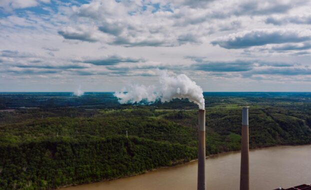 A polluted river with smokestacks in the foreground. Image by Kelly from Pexels