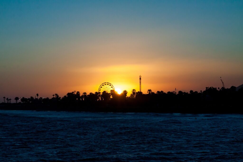The silhouette of a Ferris wheel against the setting sun.