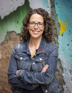 Photo of Jane Friedman, a white woman with brown hair and glasses, wearing a denim jacket and smiling