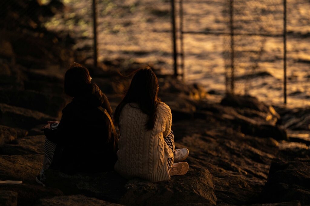 Two people sitting on a beach at sunset